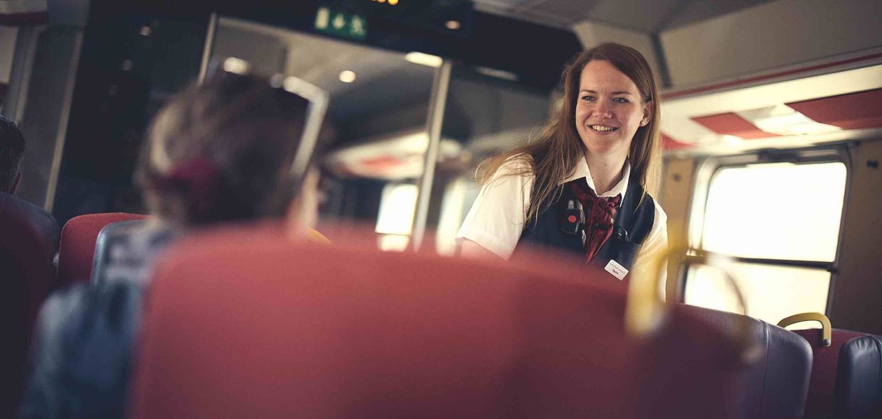 Happy train attendant conducting ticket inspection.